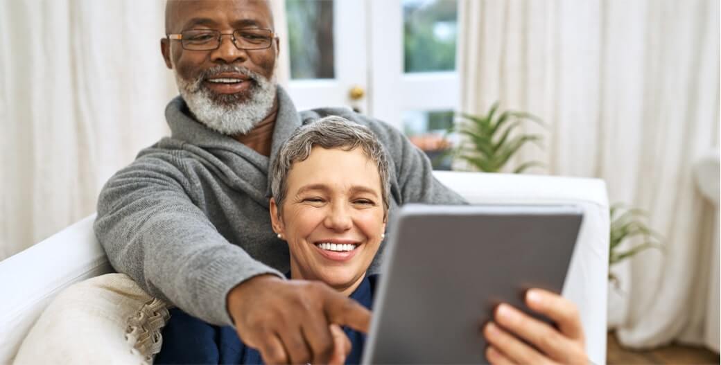 Older couple sitting on the couch with a computer tablet